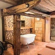 Freistehende Badewanne vor einer Holzwand in der Hütte.