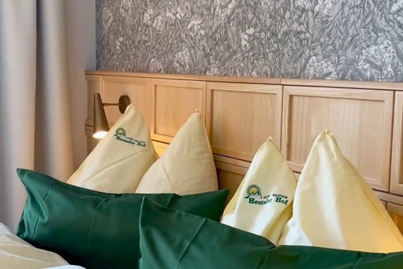 Bett im Hotelzimmer mit gelber & grüner Bettwäsche.